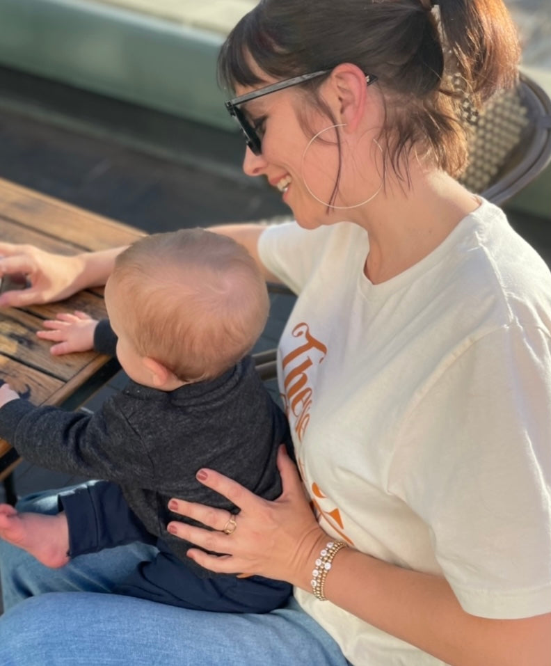 Mother wearing personalised bracelets sitting with baby on her lap 